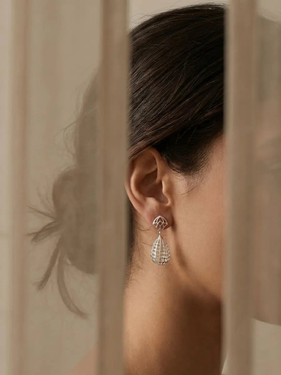 Silver teardrop earrings with intricate cage style design on model
