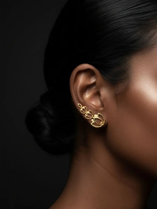 Gold climber earring in a floral design worn by model